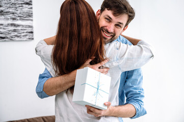Young happy man receive gift from lovely wife and hug tender her