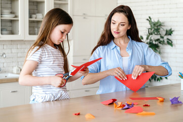 Woman folding origami paper, making craft toy with child