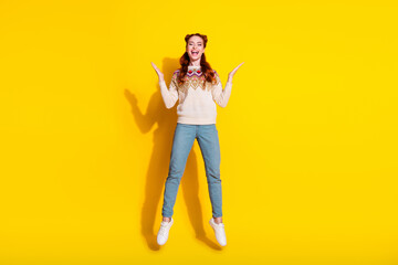 Photo portrait of attractive young woman jump raise hands excited dressed stylish knitted warm outfit isolated on yellow color background
