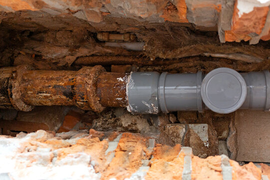 Sewer pipe repair. Partial replacement of the old cast iron pipe with a new plastic one.