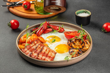 Traditional full English breakfast with fried eggs, sausages, beans, mushrooms, grilled tomatoes and bacon served on grey table. top view. copy space for text