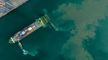 Tug boat pulling Cargo Container Ship into Cargo international sea port. Freight forwarding service...