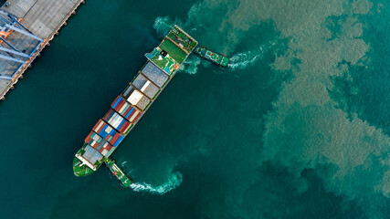 Tug boat pulling Cargo Container Ship into Cargo international sea port. Freight forwarding service...