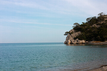 Naklejka premium beautiful view of cliffs with trees on the Mediterranean coast, beach, sky and sea in the background