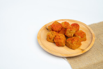 Crispy tofu in a wooden plate with a sprinkling of balado powder