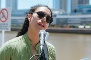 portrait of young latin man artist singer and guitarist singing pop music on street