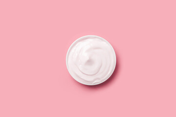 Cream jar of white  on a pink background.