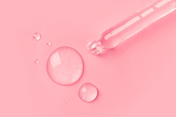The gel dripping from the dropper is transparent in the form of round droplets  on a pink...