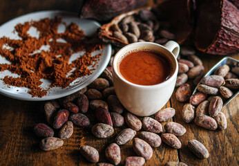 Hot chocolate drink,cocoa drink and natural cocoa powder with brown cocoa beans and dry cacao pod  on a vintage wooden table.