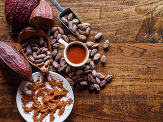 Top view of hot chocolate drink,cocoa drink and natural cocoa powder with brown cocoa beans and dry cacao pod  on a vintage wooden table.