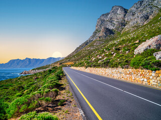 Winding road R44 along indian ocan with lush bush and rugged mountain at Kogel Bay, Cape Town,...