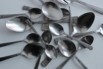 Heap Of Table Spoons And Dessert Spoons On White Plastic Cutting Board. Eating Utensils Concept...