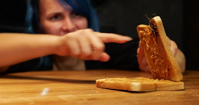 Woman touches large cockroach stuck to peanut butter in sandwich with her finger. An unexpected find in freshly cooked food. Looks like someone's breakfast is ruined today