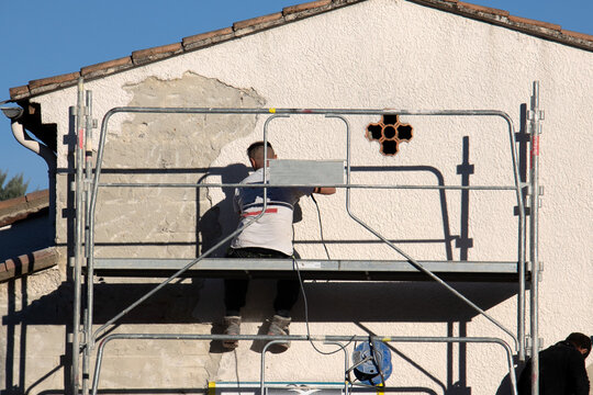 travailleurs du b&acirc;timent faisant un ravalement de la fa&ccedil;ade d'une maison