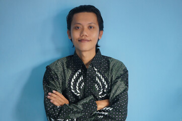 Handsome Asian man wearing batik shirt happy and smiling looking at the camera