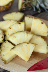 Pineapple (ananas) slices on wooden cutting board. Bromelain food, healthy yellow tropical fruit chopped in pieces.
