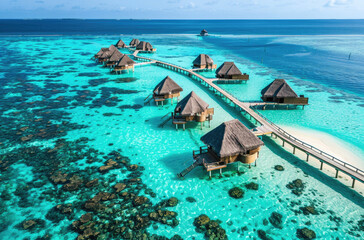 An aerial view of an island in the Maldives with overwater bainment and cabanas, and clear blue...