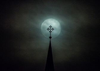 mistyczny obraz księżyca w pełni i krzyża na wieży kościoła w nocy we mgle