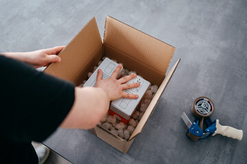 Ein Arbeiter verpackt ein Paket, verschließt es mit Klebeband, macht fertig zum Versand