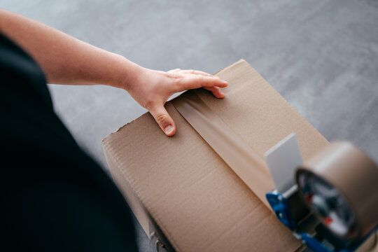 Ein Arbeiter verpackt ein Paket, verschlie&szlig;t es mit Klebeband, macht fertig zum Versand