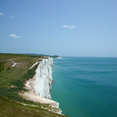 A section of the white cliff taken from the top. The cliff is covered with green grass on the top....