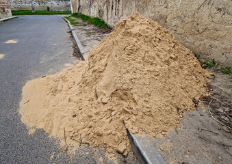 on the street lies a folded pile of sand or red clay. repair of the road of the house backfill gas...