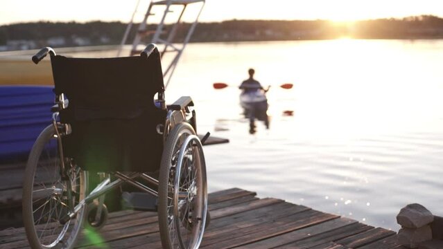 A man with a disability is kayaking against the backdrop of a golden sunset