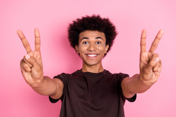 Closeup photo of cheerful guy in brown t shirt showing you double v sign hello from new country...
