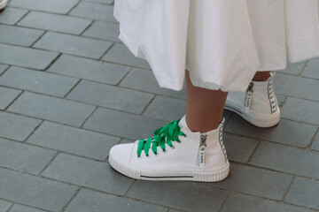 A woman wearing a white dress and green laces on her shoes