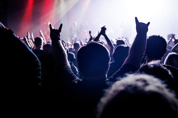 Live concert, where silhouetted figures are immersed in the euphoria of music, their hands raised...