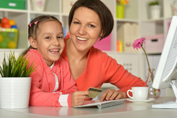 Smiling mother and daughter using computer for online shopping.