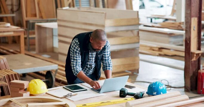 Black man, architect and workplace with laptop in desk for building plan, ideas and design. Mature person, technology and engineer in warehouse or startup business for construction project.