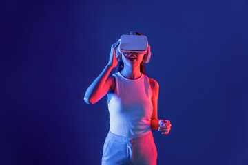 Smart female stand in cyberpunk neon light wearing VR headset connecting metaverse, futuristic...