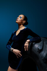 A young African American woman stands beside a towering black bag in a studio setting. © LIGHTFIELD STUDIOS