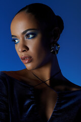 Young African American woman in a black dress with bag, captivating blue eyes.