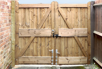 Double wooden gates on driveway with lock and drop bolts
