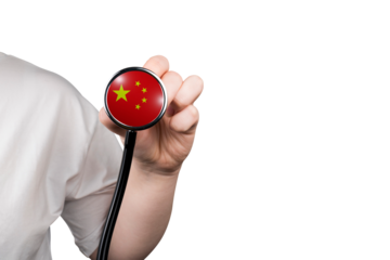The head of a medical stethoscope in the form of the Chinese flag in a hand (close-up) on a transparent background. Chinese medicine concept