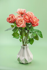 A bouquet of roses in vase on a pastel green background. Blooming flowers, festive concept
