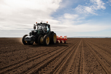 Farmer with tractor seeding crops at field - 777309663