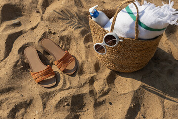 Jute beach bag and flip flops on the sand. Summer vacation lifestyle concept. 