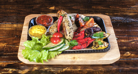 A tray of food with a variety of vegetables and meat. The tray is on a wooden table