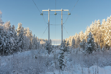 Power lines cross the countryside in a snowy and sunny sweden