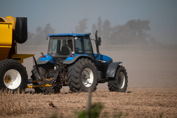 Tractor azul que traslada maquinaria en campo argentino