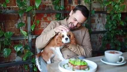 A man with a dog in a cafe . Dog friendly establishments
