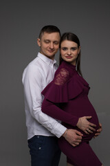 portrait of a pregnant couple on a grey background close up, fashion pregnant model posing in studio, pregnant woman stands on a grey background, studio shoot