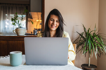 One young girl or woman is using her laptop to work from home in the morning while drinking coffee