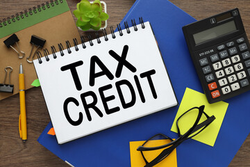 tax credit . Business concept. glasses on a yellow notepad on a blue folder near the calculator....