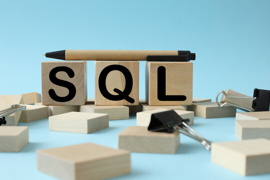blue background and wooden blocks. black pen on wooden cubes. text SQL