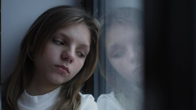 Young sad girl looking out of window