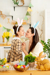 Easter family traditions. A young mother and daughter are playing with colorful eggs in the kitchen, enjoying the holiday, the family is preparing for a bright Easter by painting eggs